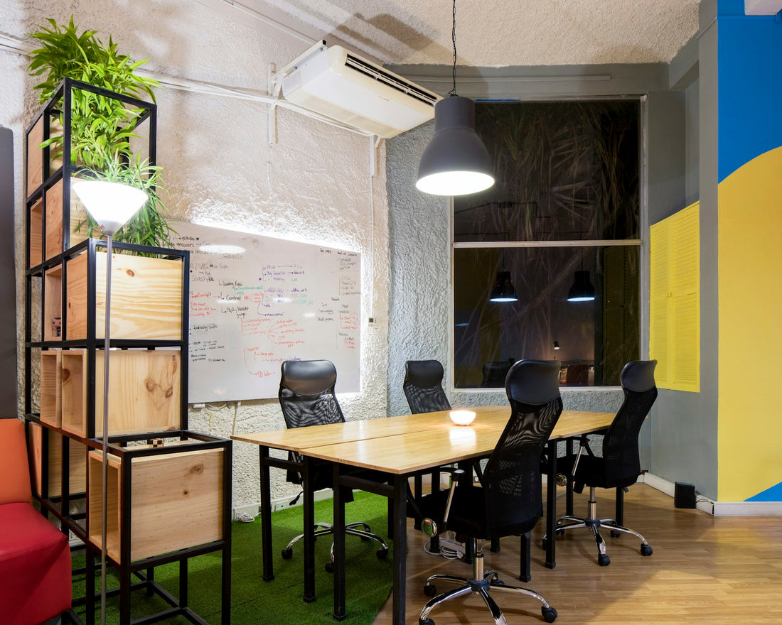 Leerer Meetingraum mit Holztisch, schwarzen Stühlen und Whiteboard an der Wand